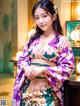 A woman in a purple and green kimono posing for a picture.