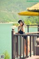 A woman in a black bathing suit and hat standing on a balcony.