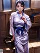 A woman in a blue and white kimono standing in front of a window.