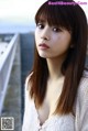 A woman with long brown hair standing on a bridge.