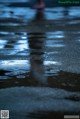 A person walking on a wet sidewalk in the rain.