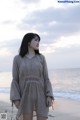 A woman standing on a beach next to the ocean.