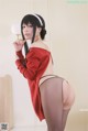 A woman in a red sweater and black pantyhose posing for a picture.