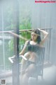 A woman sitting on a chair in front of a window.